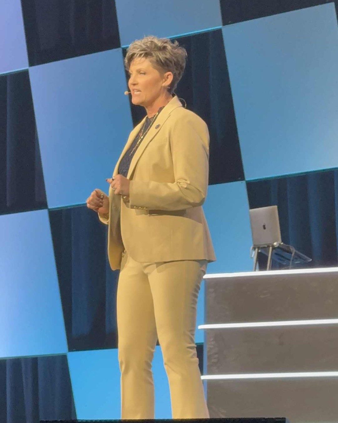 Marci Nettles speaking on stage with a headset microphone